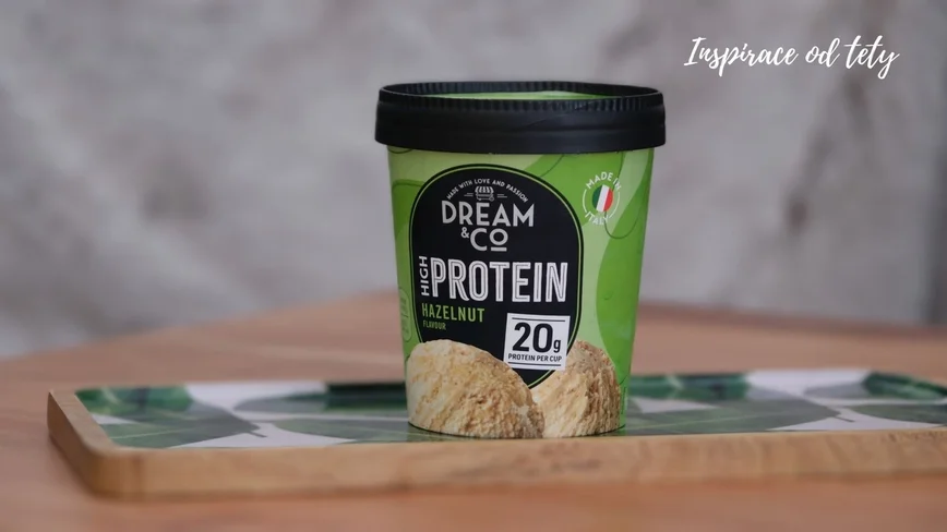 Kelímek oříškové proteinové zmrzliny na tácku.