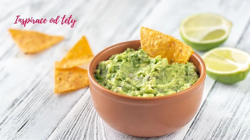 guacamole v misce, limetky a nachos okolo jako dekorace