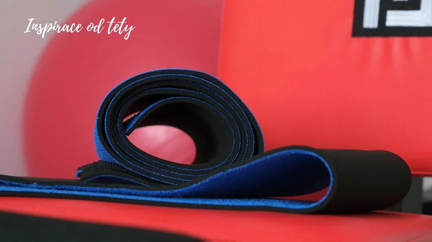 Neoprenové pásy na hubnutí na posilovací lavici ve fitness centru.